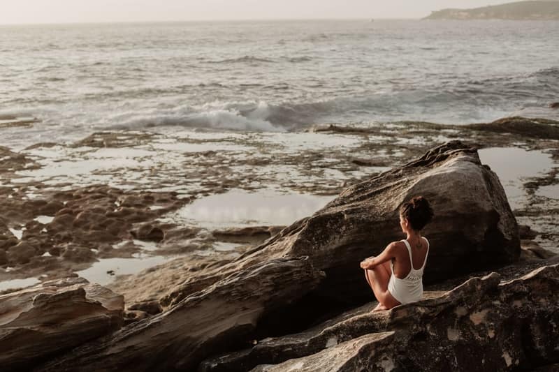 A woman reminiscing their self by the sea while studying abroad. 