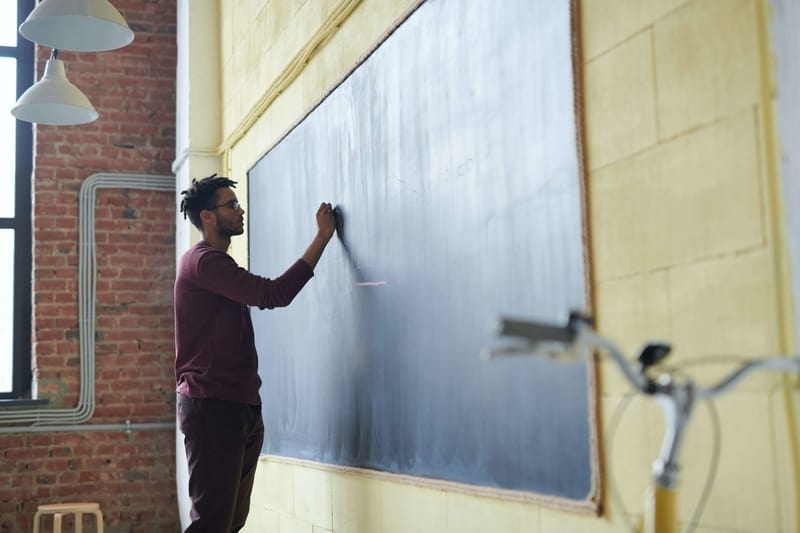 A teacher writing on the blackboard to the students studying abroad. 